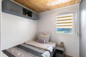 a small bedroom with a bed and a window at Madera Concordiasee in Friedrichsaue