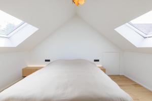 a bedroom with a large white bed with skylights at Apartment L'O Reine, B&B in Sint-Pieters-Leeuw