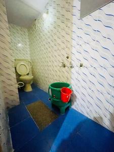 a bathroom with a green bucket and a toilet at Casablis homestay in Mysore