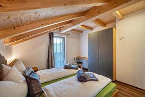 two beds in a room with wooden ceilings at Krämerhof Apt Villnösser Geisler in Rodengo