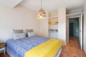 a bedroom with a bed with a yellow and blue blanket at Apartamento Davasa in Armação de Pêra +15 photos