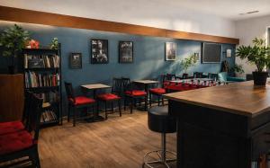 a bar with tables and chairs and a book shelf at Koala Hostel in Milan