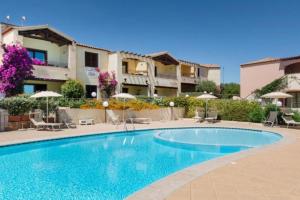 a pool with chairs and umbrellas in front of a building at Lazulite - Sardinia Suite in Murta Maria