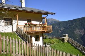 a house with a balcony with flowers on it at Thalhof Laugen in Ultimo