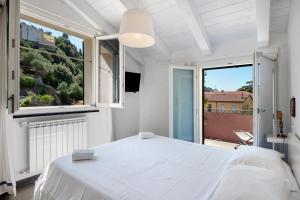 a white bedroom with a bed and a large window at La terrazza di via Daneri 2 in Bonassola