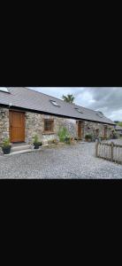 a stone house with a wooden door and a fence at Ystrad Fach Farm in Llangendeirne
