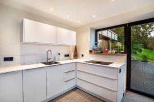 a kitchen with white cabinets and a large window at Waldlux Luxus-Chalet Brennhus in Kappelrodeck +24 photos