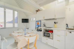 a kitchen with white cabinets and a table and chairs at La Cabane des Goélands Rieurs in Dinard