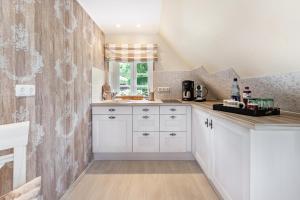 a kitchen with white cabinets and a window at My Little Rose Cottage in Dörpling