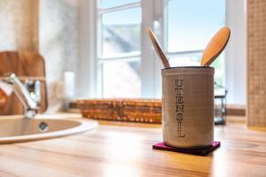 a cup with utensils sitting on a kitchen counter at My Little Rose Cottage in Dörpling +14 photos