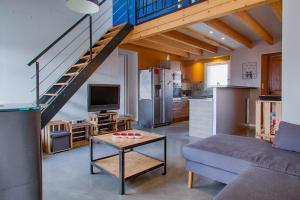 a living room with a couch and a kitchen with a staircase at Gîte Ludomi in Vercheny