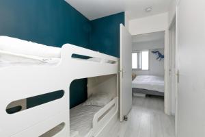 a bedroom with white bunk beds and a blue wall at Appartement front de mer - Terrasse in Pornichet