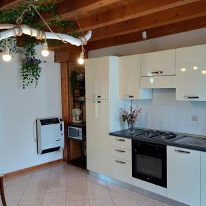 a kitchen with white cabinets and a stove top oven at La Casa del Zuf in Carlino