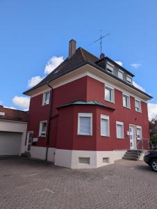 a red and white house with a parking lot at Ferienwohnung Beck in Ansbach