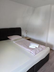 a white bed with a black headboard and pink sheets at Ferienwohnung Beck in Ansbach