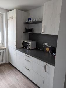 a kitchen with white cabinets and a microwave on a counter at Ferienwohnung Beck in Ansbach