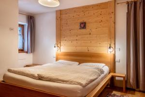 a bed in a room with a wooden wall at Dolomitc Tobià in Campitello di Fassa