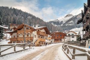 a snowy street in a mountain village with buildings at Dolomitc Tobià in Campitello di Fassa