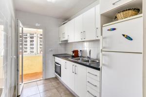 a white kitchen with a sink and a refrigerator at Escala Riells in L'Escala +17 photos