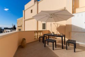 a balcony with a table and chairs and an umbrella at Casa vacanza Sotto La Lizza in Alezio