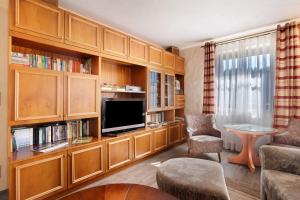 a living room with wooden cabinets and a flat screen tv at Ferienhaus Pöhlbergblick Schindelba in Großrückerswalde