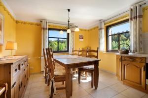 a dining room with yellow walls and a wooden table and chairs at Ferienhaus Pöhlbergblick Schindelba in Großrückerswalde