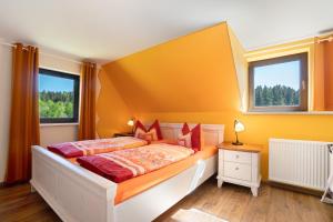 a bedroom with a bed and two windows at Ferienhaus Pöhlbergblick Schindelba in Großrückerswalde