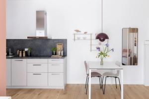 a kitchen with white cabinets and a white table at Koje in Böhl +11 photos