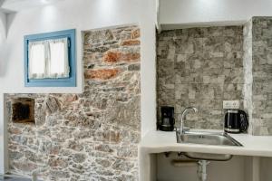 a kitchen with a sink and a stone wall at Politimis Studio N5 in Amorgos +19 photos
