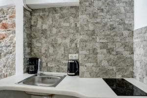 a kitchen with a sink and a stone wall at Politimis Studio N5 in Amorgos