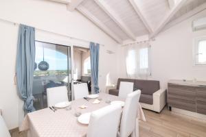 a white living room with a table and a couch at Attico con vista mare a Budoni in Budoni