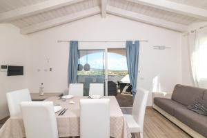 a white living room with a table and a couch at Attico con vista mare a Budoni in Budoni +12 photos