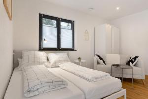 a white bedroom with two beds and a window at Meerrettichnest in Appenweier