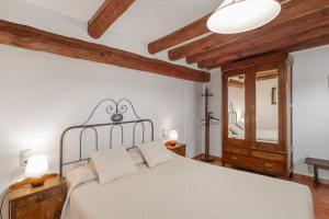 a bedroom with a white bed and wooden ceilings at Masoveria De Vilanova in Sagás +34 photos