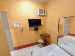 a room with a tv on the wall and a table at MCT Hotel in Manila
