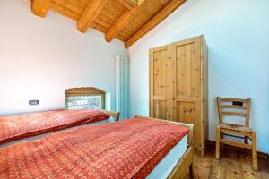 a bedroom with a bed and a chair at Agritur Piazera Attico in Ronzo Chienis