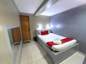 a small bedroom with a bed with red pillows at MCT Hotel in Manila +13 photos