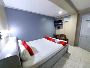 a bedroom with a white bed with red pillows at MCT Hotel in Manila
