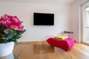 a living room with a red ottoman and a vase with flowers at Traumblick in Bad Liebenzell