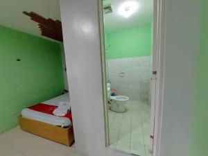 a bathroom with a bed and a toilet and a mirror at MCT Hotel in Manila