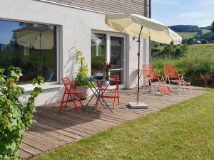 a patio with a table and chairs and an umbrella at Ferienwohnung Waldmeisterzimmer in Sankt Peter