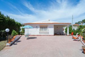 a house with a patio and a blue umbrella at Villa Nonna Anna a Plemmirio in Syracuse