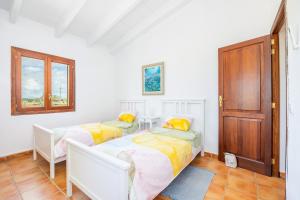 two beds in a white room with a door at Casita Rafal Roig in Maria de la Salut +19 photos