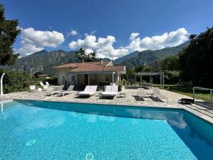 a swimming pool with lounge chairs and a house at Villa Romantica Lake Idro in Bagolino