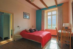 a bedroom with a bed with a red blanket and a window at Gite 8 personnes in Bégard