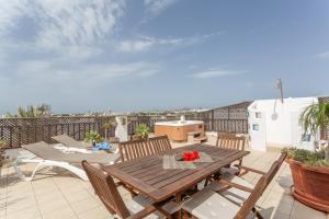 a patio with a wooden table and chairs on a balcony at Penthouse con Jacuzzi in Costa Teguise