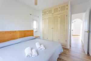 a bedroom with a white bed with towels on it at Son Bou Gardens Plus 2 in Son Bou