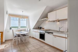 a kitchen with white cabinets and a table in it at Wohnung Hallighof in Honkenswarft