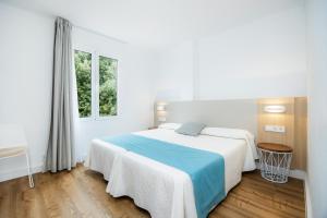a white bedroom with a large bed and two windows at Apartament Massanet 1c in Canyamel