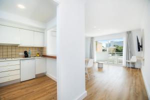 an open kitchen and living room with white cabinets at Apartament Massanet 1c in Canyamel